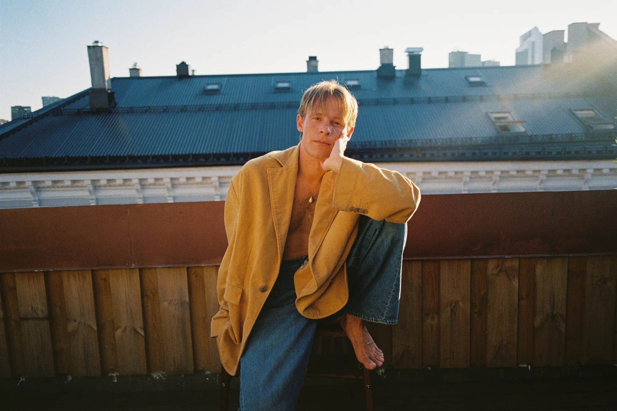 Sondre Justad i gul jakke på en takterrasse i Oslo, analogt foto
